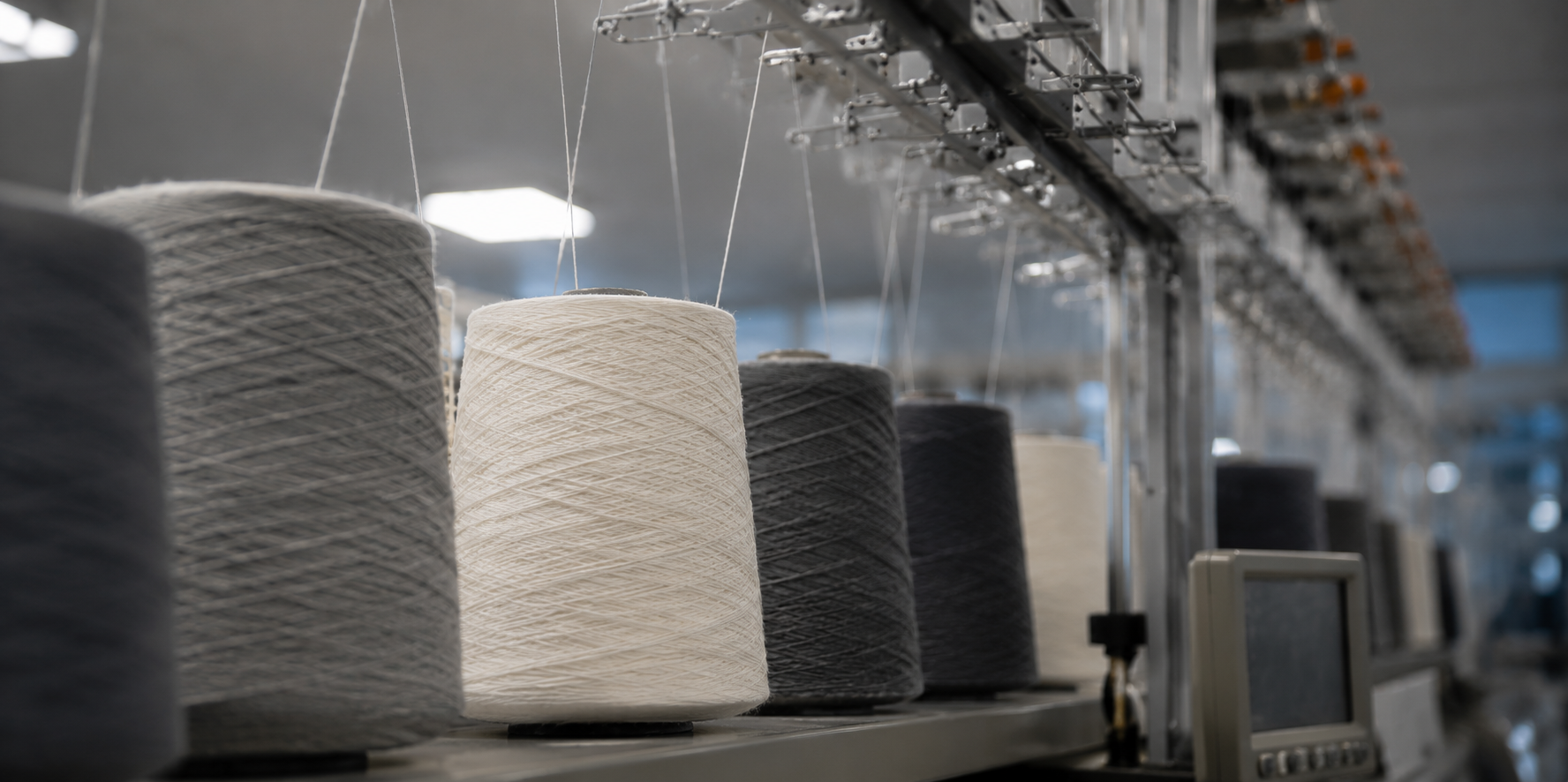Close-up of a knitting machine with yarn on the production floor